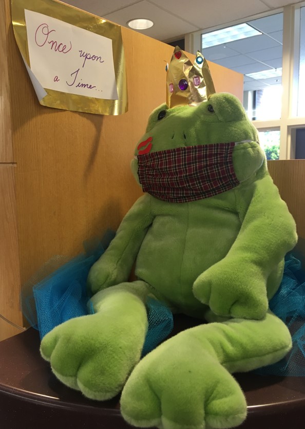 A stuffed frog wearing a face mask.